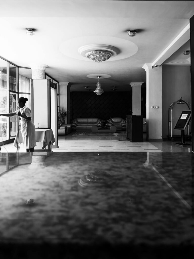 Grayscale Photo of a Woman Cleaning inside the House