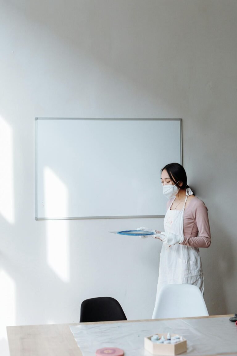 Woman in Mask and Apron Standing by Whiteboard